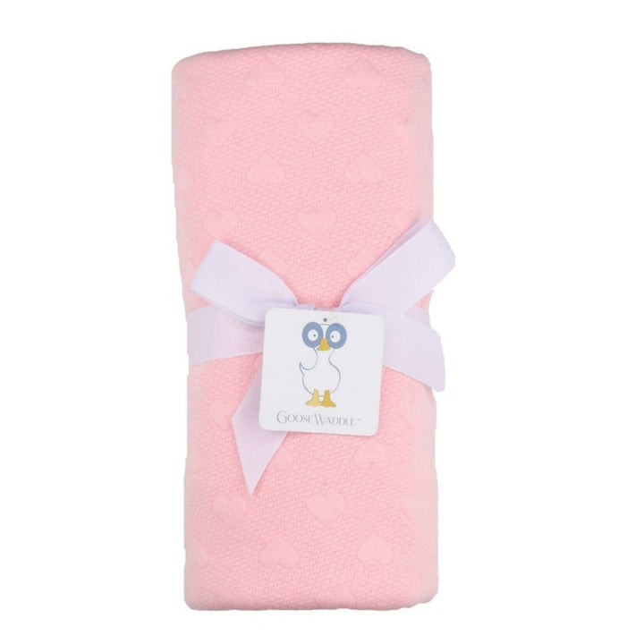A pink knit blanket with a white bow and tag displaying the brand name.