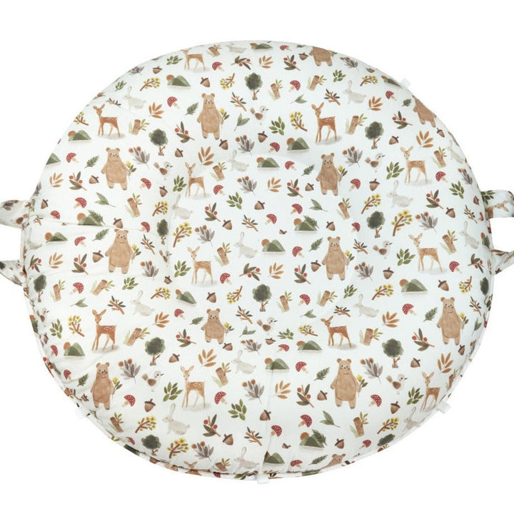A round floor cushion with a pattern of animals and foliage in neutral colors.