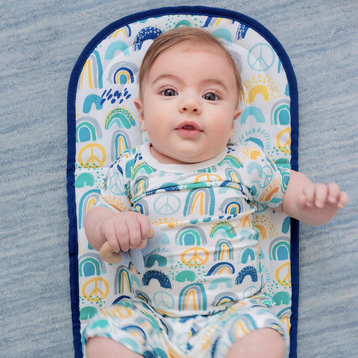 Baby in a colorful outfit lying on a blue and white patterned changing mat.