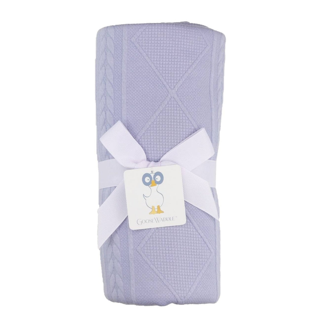A purple knit blanket wrapped with a white ribbon and tagged with a GooseWaddle brand tag.